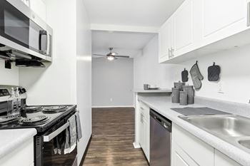 A modern kitchen with white cabinets and a black stove top.